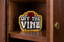 A yellow Off The Vine pouch inside a wooden cabinet, with a lock visible on the open door.